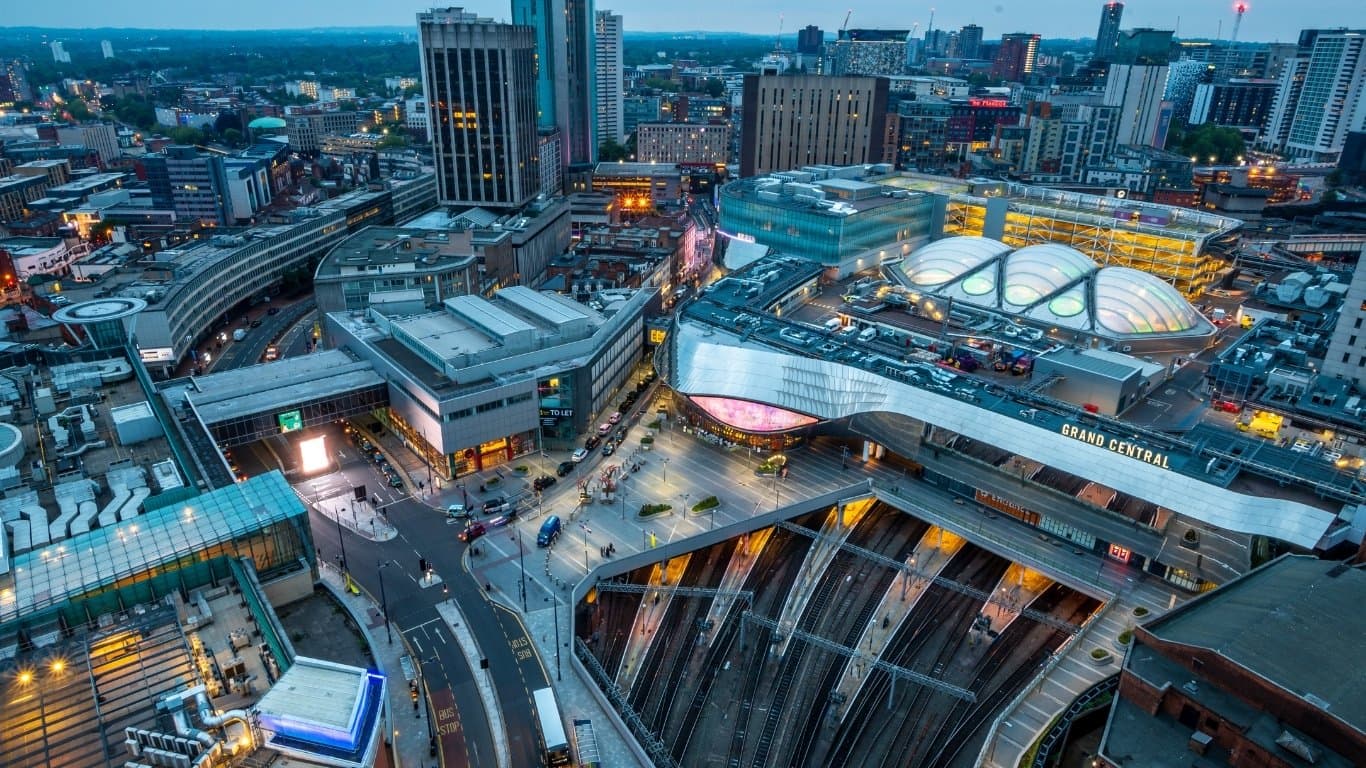 An aerial view of Birmingham city centre at dusk, with Grand Central and New Street station in the foreground