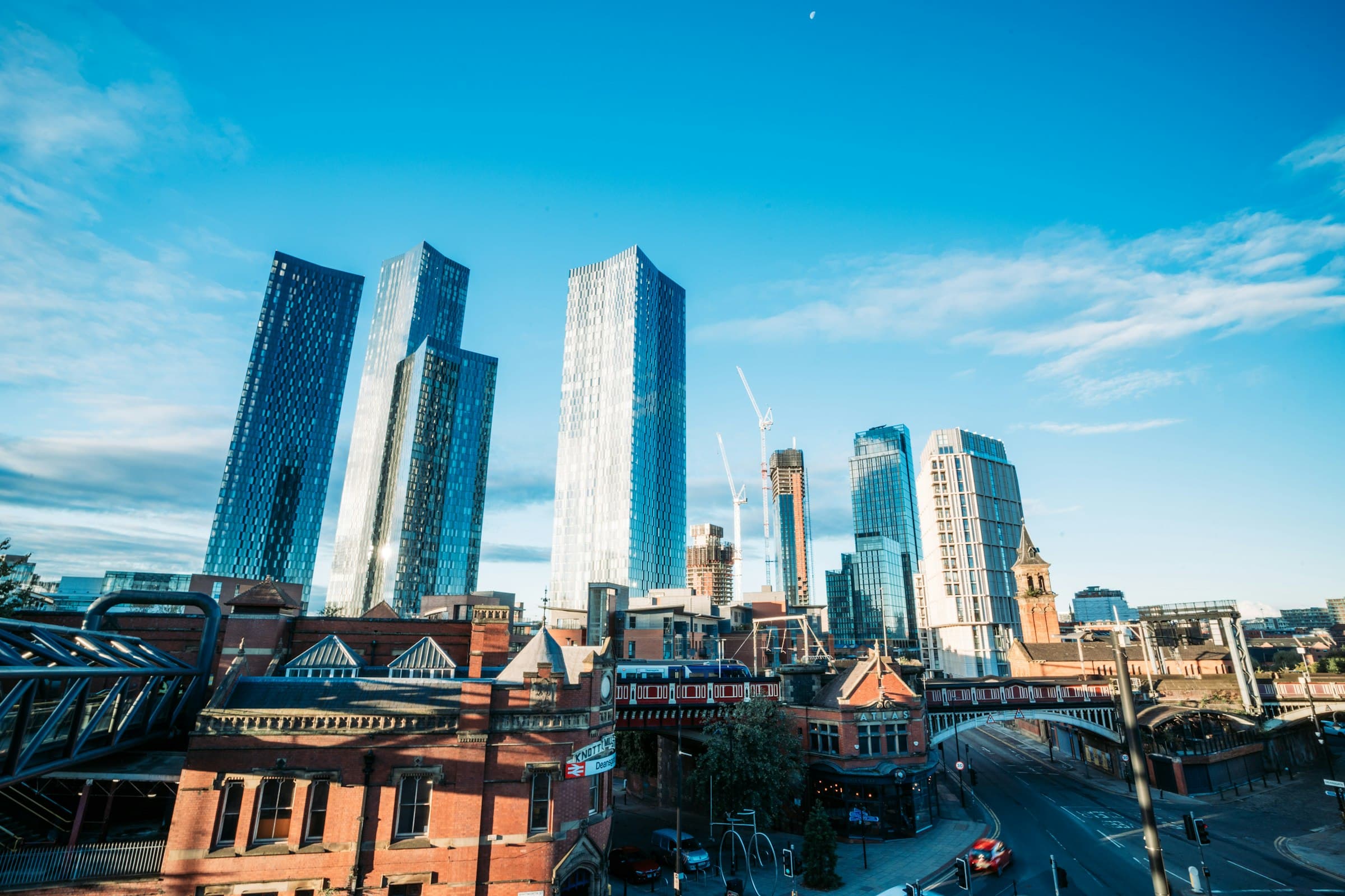 The Deansgate Square towers rising above red brick Victorian buildings in Manchester city centre